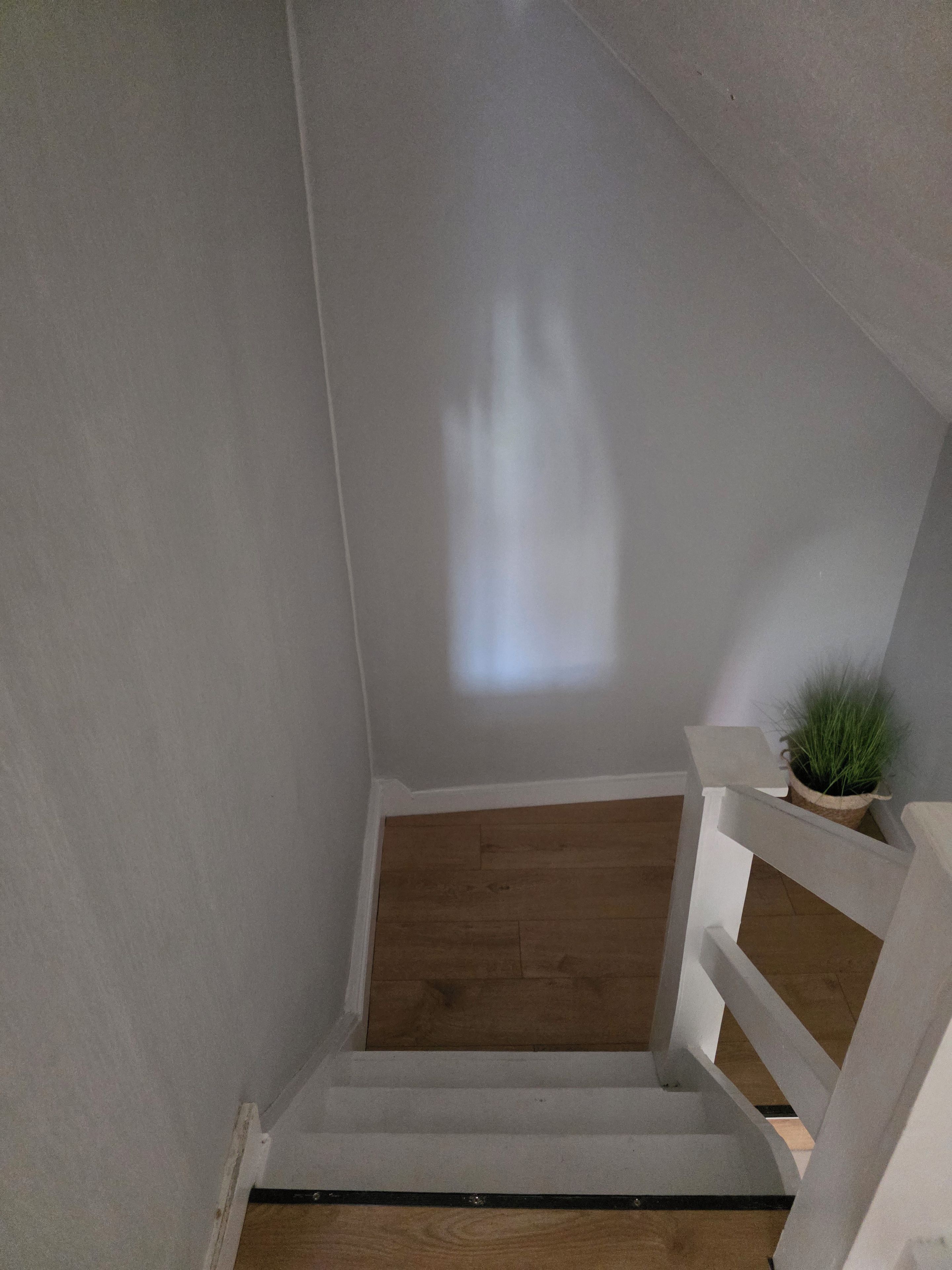 A staircase with a wooden floor and white railings, leading to a higher level.