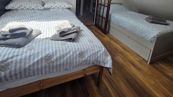 A bedroom with a sloped ceiling, a bed with striped bedding, a bedside table, and a wooden floor.