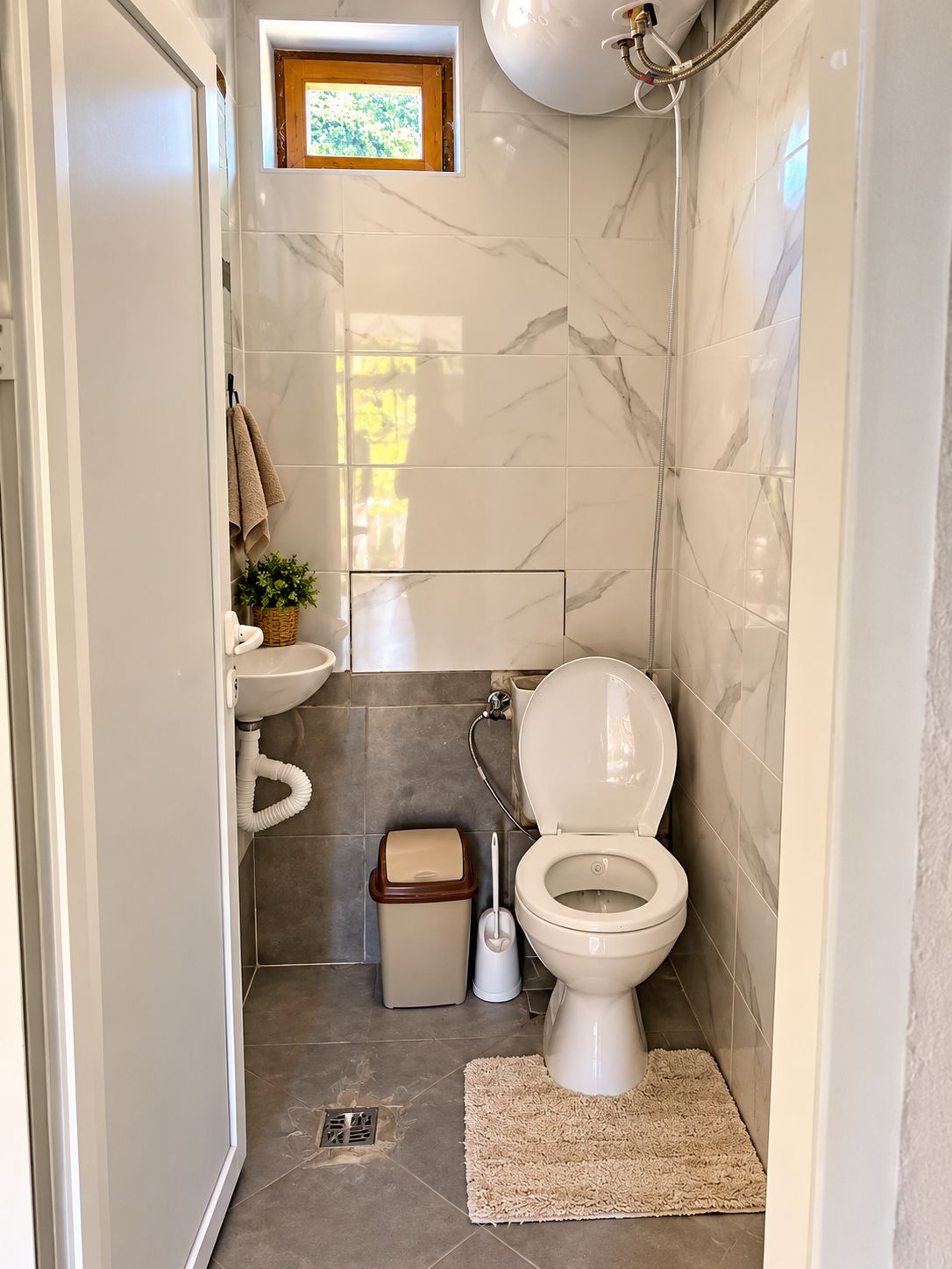 A compact bathroom with a toilet, sink, and shower.
