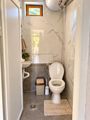 A compact bathroom with a toilet, sink, and shower.