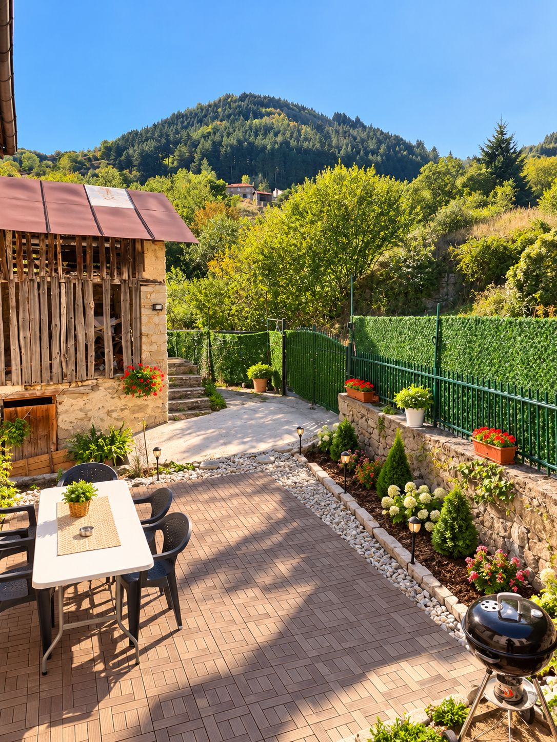 A patio area with a table and chairs, a barbecue grill, and a stone wall with potted plants.