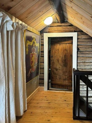 A wooden interior with a sloped ceiling, a door, and a framed picture on the wall. - Idyll, history and nature – all in one place (Hornnes)