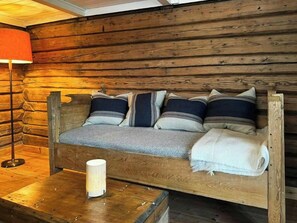 A wooden log cabin interior with a bed, pillows, a lamp, and a table. - Idyll, history and nature – all in one place (Hornnes)
