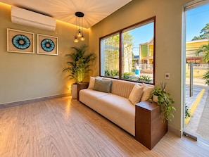 A modern living room with a sofa, a large window, and a potted plant. - New Listing (Jarabacoa)