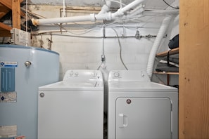 Une buanderie équipée de deux machines à laver à chargement frontal et d’un grand chauffe-eau.