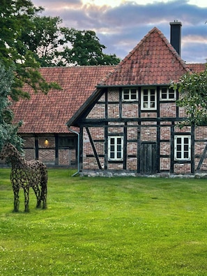 Ein traditionelles Fachwerkhäuschen mit rotem Ziegeldach, Schornstein und Rasen.