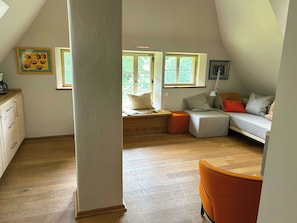Ein gemütliches Schlafzimmer im Dachgeschoss mit einem Hochbett, einer kleinen Sitzecke und einem Fenster, das für natürliches Licht sorgt.