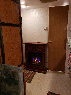 Ein Zimmer mit Kamin, einer Holztür und einem Fliesenboden.