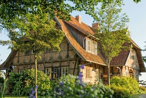 Ein traditionelles Backsteinhaus mit steiler Satteldachform, zahlreichen Fenstern und einem gepflegten Garten.