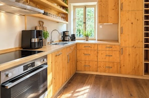 Eine moderne Küche mit Holzschränken, einem Edelstahlherd und einer Kaffeemaschine.