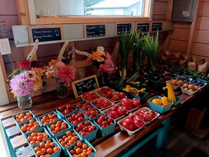 A produce stand with various vegetables and flowers for sale.