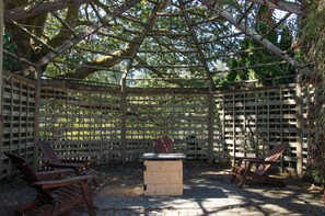 A wooden pergola structure with a bench and a table in the center, surrounded by a lattice fence. - Farm stay in the heart of Metchosin, near Victoria and outdoor adventures (Victoria)