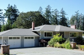 A two-story house with a garage, a chimney, and a well-maintained garden.