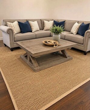 A sectional sofa with a woven rug and a wooden coffee table with a plant and a decorative item. - 2-bedroom apartment in peaceful The Plains with AC (The Plains)