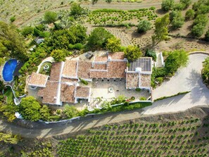 A villa with a tiled roof, surrounded by a garden and vineyard. - Rural cortijo with pool and Mediterranean views (Canillas de Aceituno)