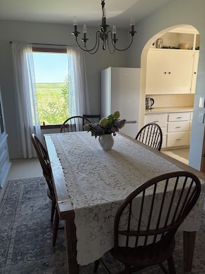 A dining area with a table set for four, a chandelier, and a view of the outdoors. - Two-story farmhouse on a working alfalfa farm, minutes from the wine district (Walla Walla)