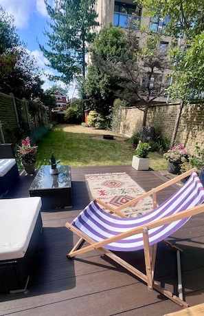 A deck with a striped lounge chair, a small table, and a white sofa. - Charming & Modern London Flat in Eltham | Great Transport Links (London)