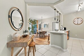Eine moderne Küche mit Kochinsel, Essbereich mit Stühlen und einem großen Spiegel an der Wand.
