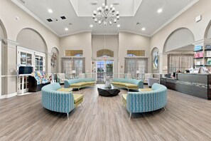 A spacious lobby with a central seating area, a reception desk, and a large chandelier. - Comfortable 3BR Family Getaway Top Location (Orlando)
