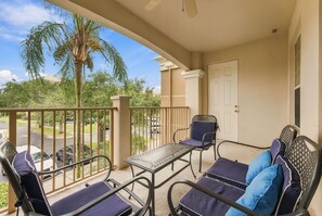 A balcony with a table and chairs, a door, and a view of a street and trees. - Work Play and Stay 3BR Prime Orlando Location (Orlando)