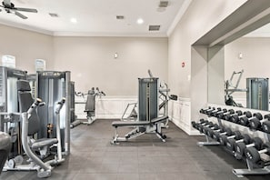Ein Fitnessstudio mit verschiedenen Trainingsgeräten, darunter Kraftgeräte und Kurzhanteln.