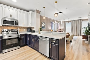 A modern kitchen with stainless steel appliances, dark cabinetry, and a central island. - Stylish Vista Cay 3BR Comfort at a Prime Location (Orlando)