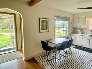 A dining area with a table and chairs, a kitchen with cabinets, a window with a view, and a door leading outside. - Charming Vintage renovated 2 story Cape Cod home near Boardman Shopping (Youngstown)