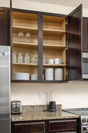 A kitchen with a dark wooden cabinet, a granite countertop, a toaster, a blender, and a stove. - Fully Furnished Mountain View Townhome 2BR/2.5BA (Broomfield)