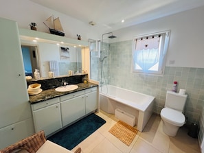 Ein Badezimmer mit Badewanne, Toilette und Duschbereich.