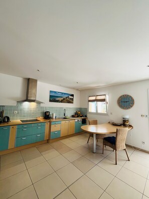Una cocina con mesa, sillas y un reloj en la pared.