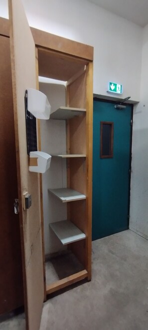 Une pièce avec une armoire en bois, une porte de couleur turquoise et une étagère blanche.