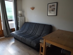 Une pièce avec un canapé à motifs, une table en bois, une lampe et un tableau encadré accroché au mur.