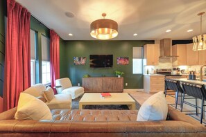 A modern living room with a leather sofa, a coffee table, and a television. - Off Broadway Nashville: Rooftop Hot Tub & Skyline Views (Nashville)