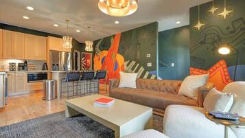 A modern living room with a sofa, coffee table, and a kitchen area with a refrigerator and microwave.