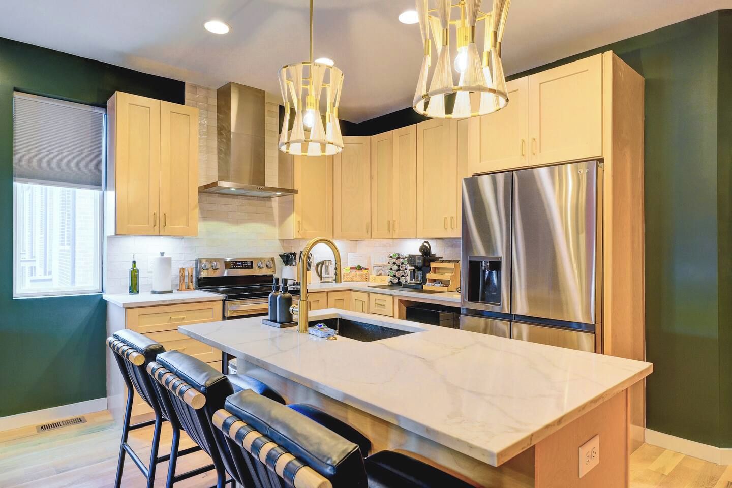 A modern kitchen with a central island, stainless steel appliances, and pendant lighting.