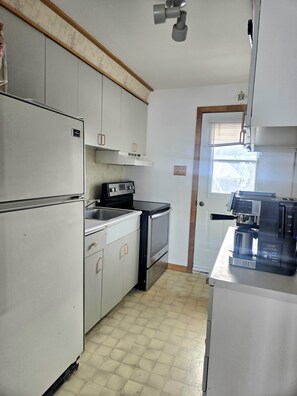 A kitchen with a refrigerator, stove, oven, and a coffee maker.