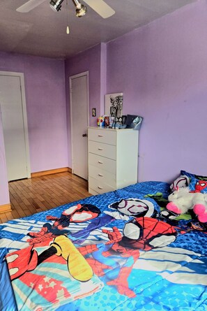 A bedroom with a bed, dresser, and a ceiling fan.