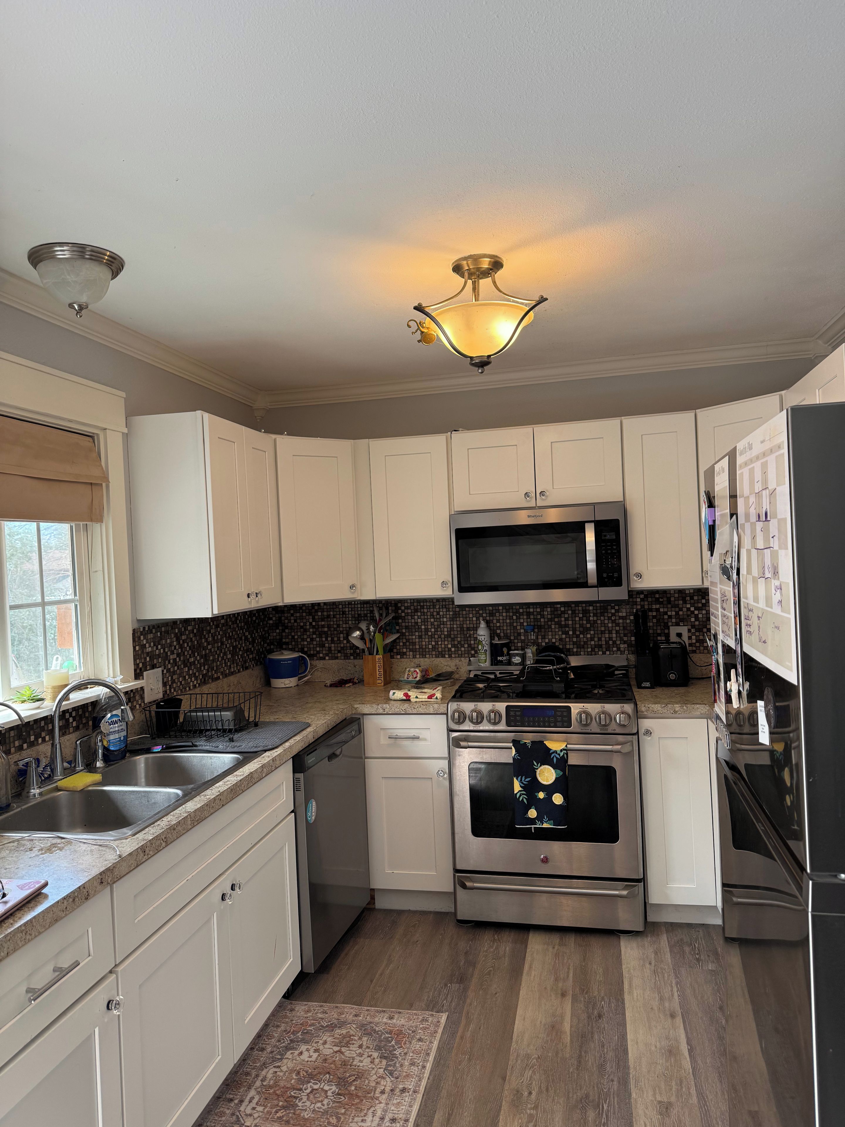 A kitchen with white cabinets, a microwave, a stove, and a refrigerator.