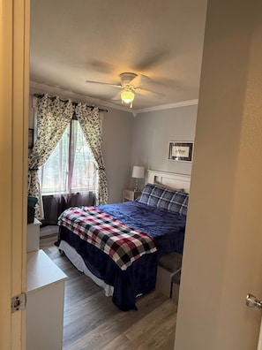 A bedroom with a bed, a ceiling fan, a window with curtains, a bedside table with a lamp, and a framed picture on the wall. - over the sugar pine retreat (Billings)