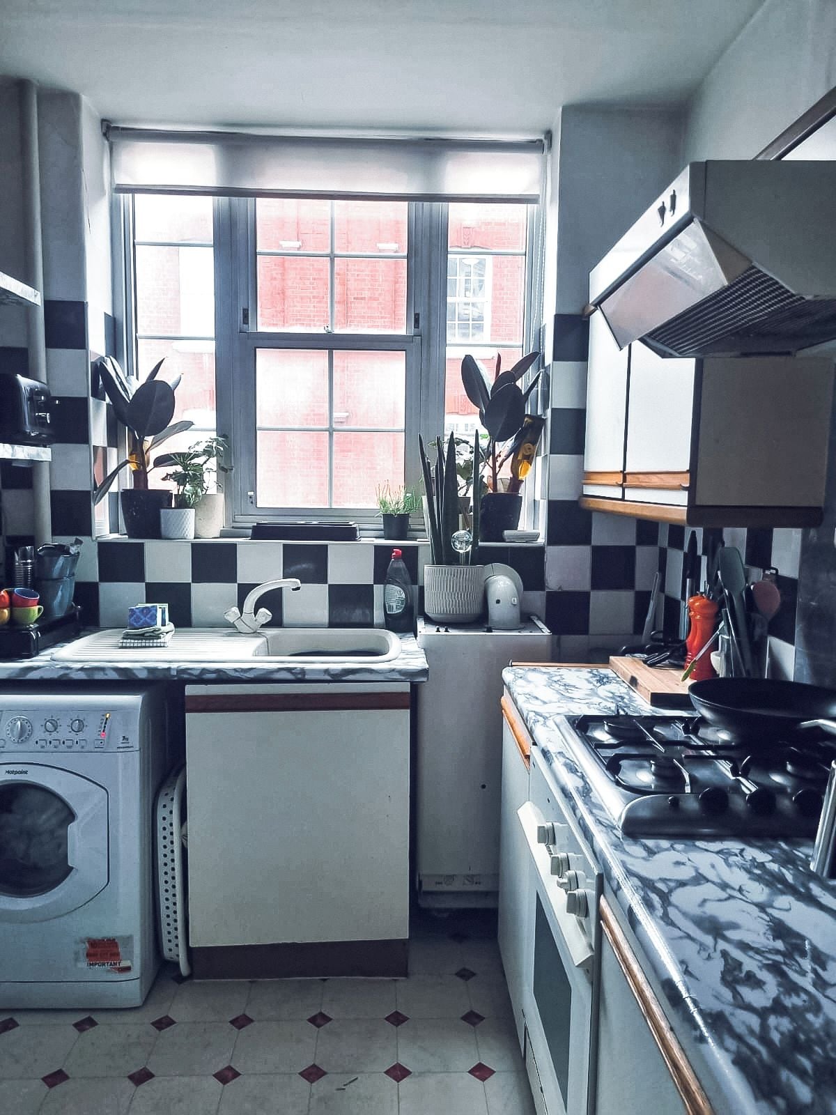 A compact kitchen with a washing machine, a stove, and a sink.