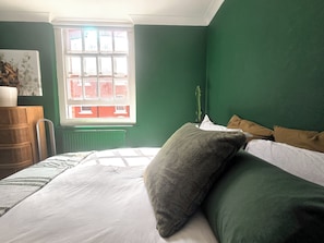 A bedroom with a bed, a window, and a green wall. - Artist's 1 Bed Apartment in Westminster / Central London (London)