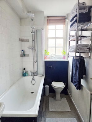 Un baño con bañera, inodoro y ventana.