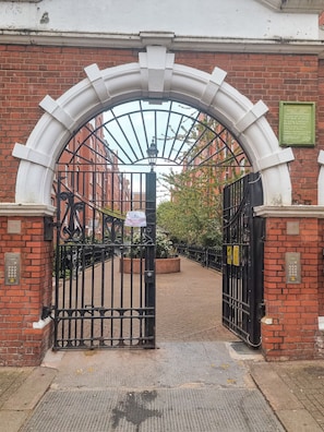 A gated entrance with a brick wall, a metal gate, and a sign indicating no motorized vehicles. - Artist's 1 Bed Apartment in Westminster / Central London (London)
