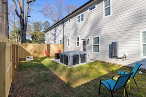 A backyard with a wooden fence, a grill, and outdoor furniture. - Charlotte Retreat - Hot Tub, Fire Pit & Uptown (Charlotte)