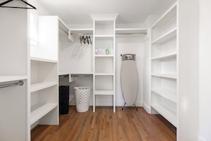 A walk-in closet with open shelving, a hanging rack, and a large iron. - Charlotte Retreat - Hot Tub, Fire Pit & Uptown (Charlotte)