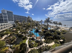 Ein Resort mit großem Pool, Palmen und Blick auf den Ozean.