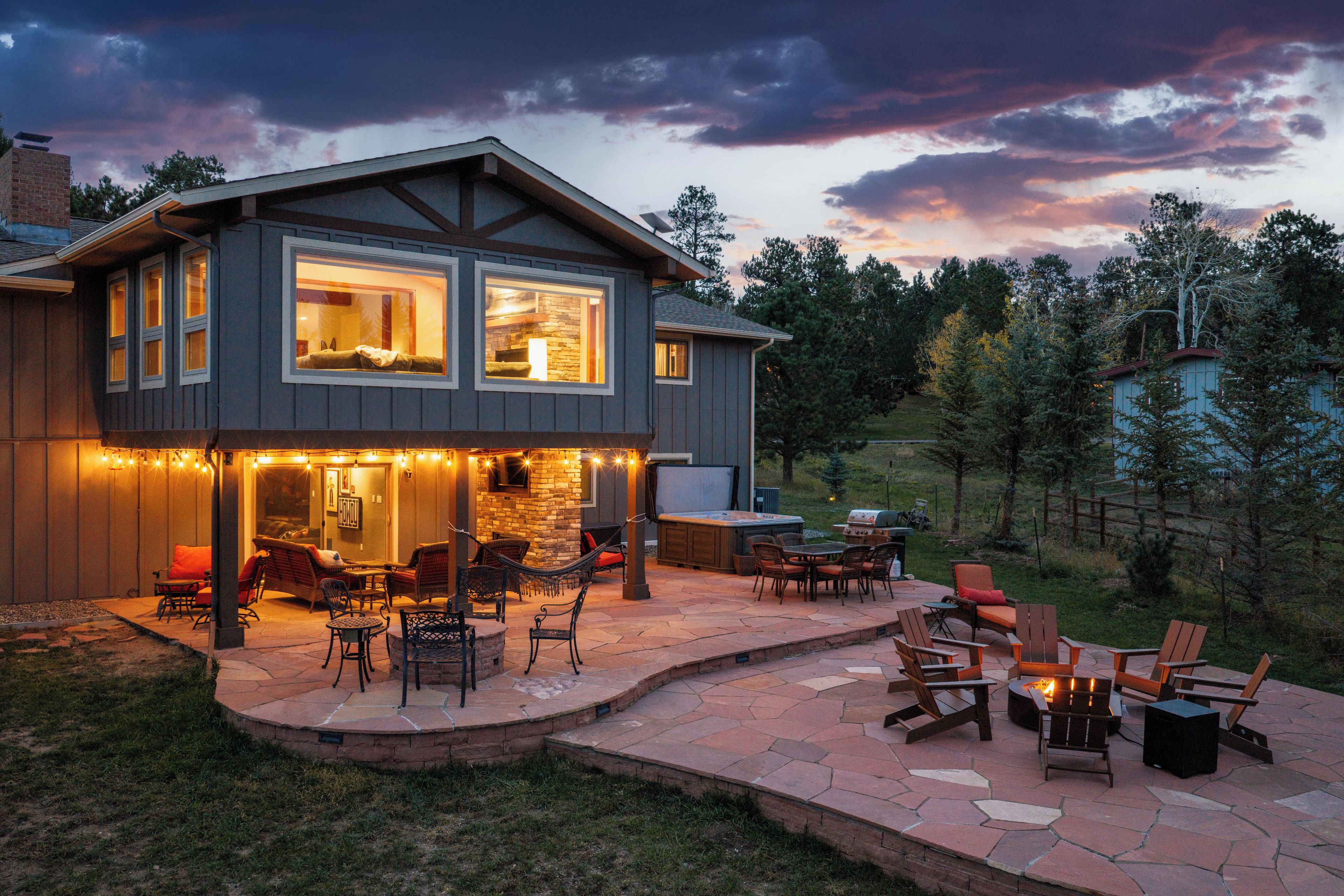 A two-story house with a patio area featuring outdoor furniture and a fire pit.