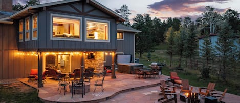 A two-story house with a patio area featuring outdoor furniture and a fire pit.