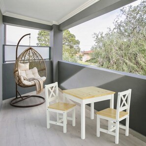 Ein Balkon mit Hängesessel, Tisch und zwei Stühlen.