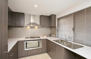 Eine moderne Küche mit dunklen Holzschränken, einer Edelstahlspüle und einem eingebauten Backofen.